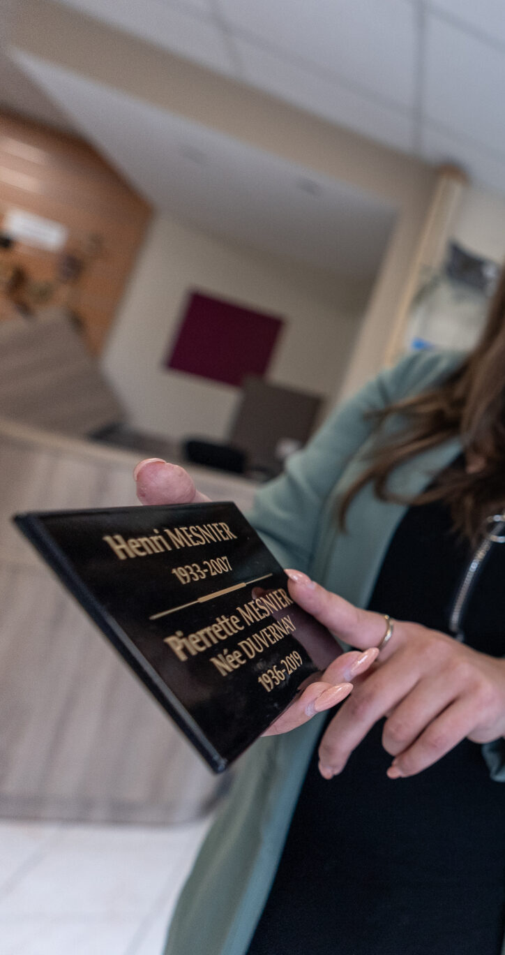 Femme tenant une plaque commémorative avec deux personnes.