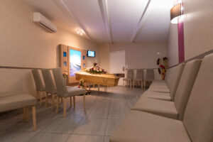 Salle de veillée funéraire avec cercueil et chaises.