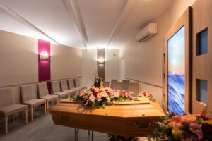 Salle de cérémonie avec cercueil et fleurs.
