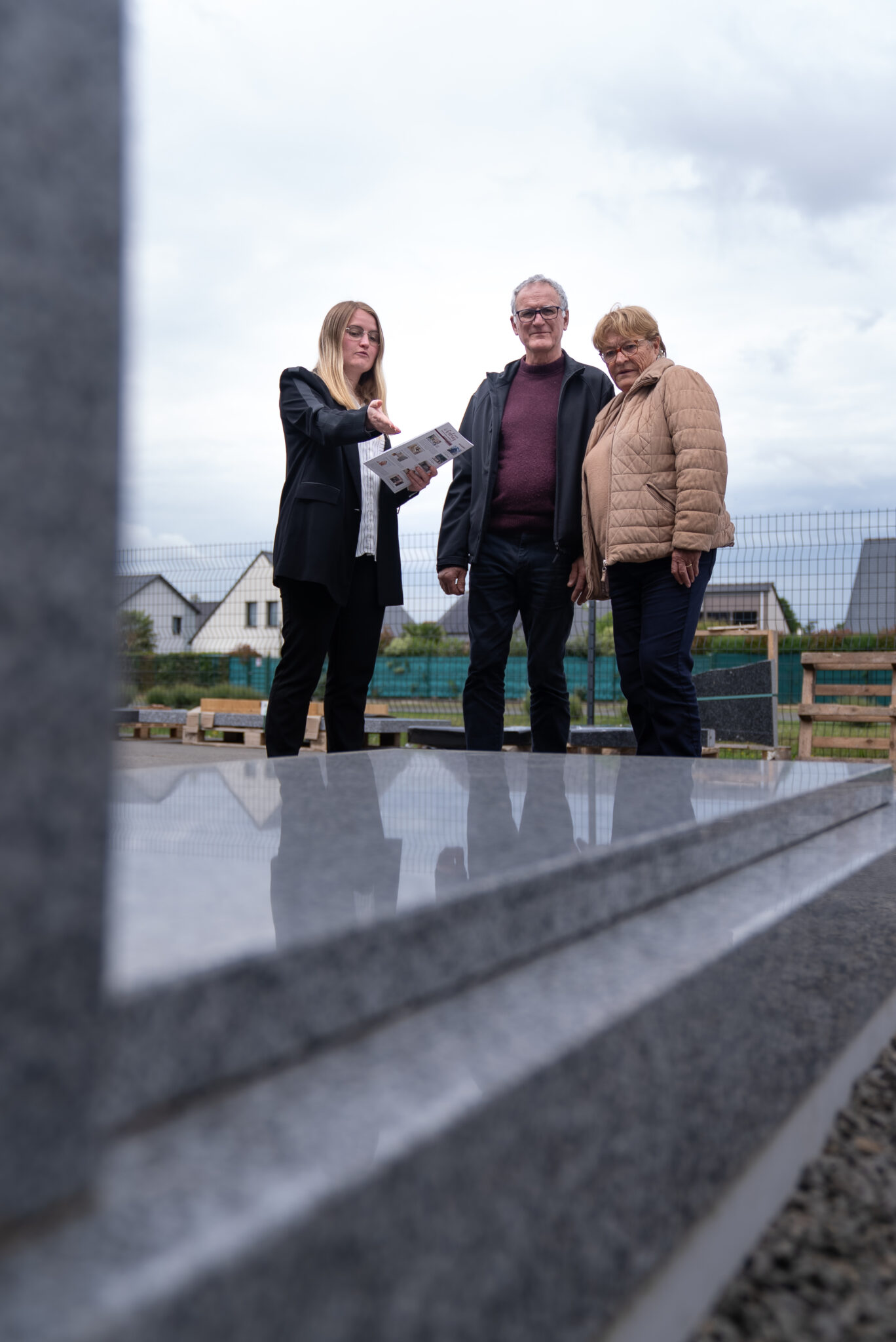 Trois personnes discutant devant une tombe grise.