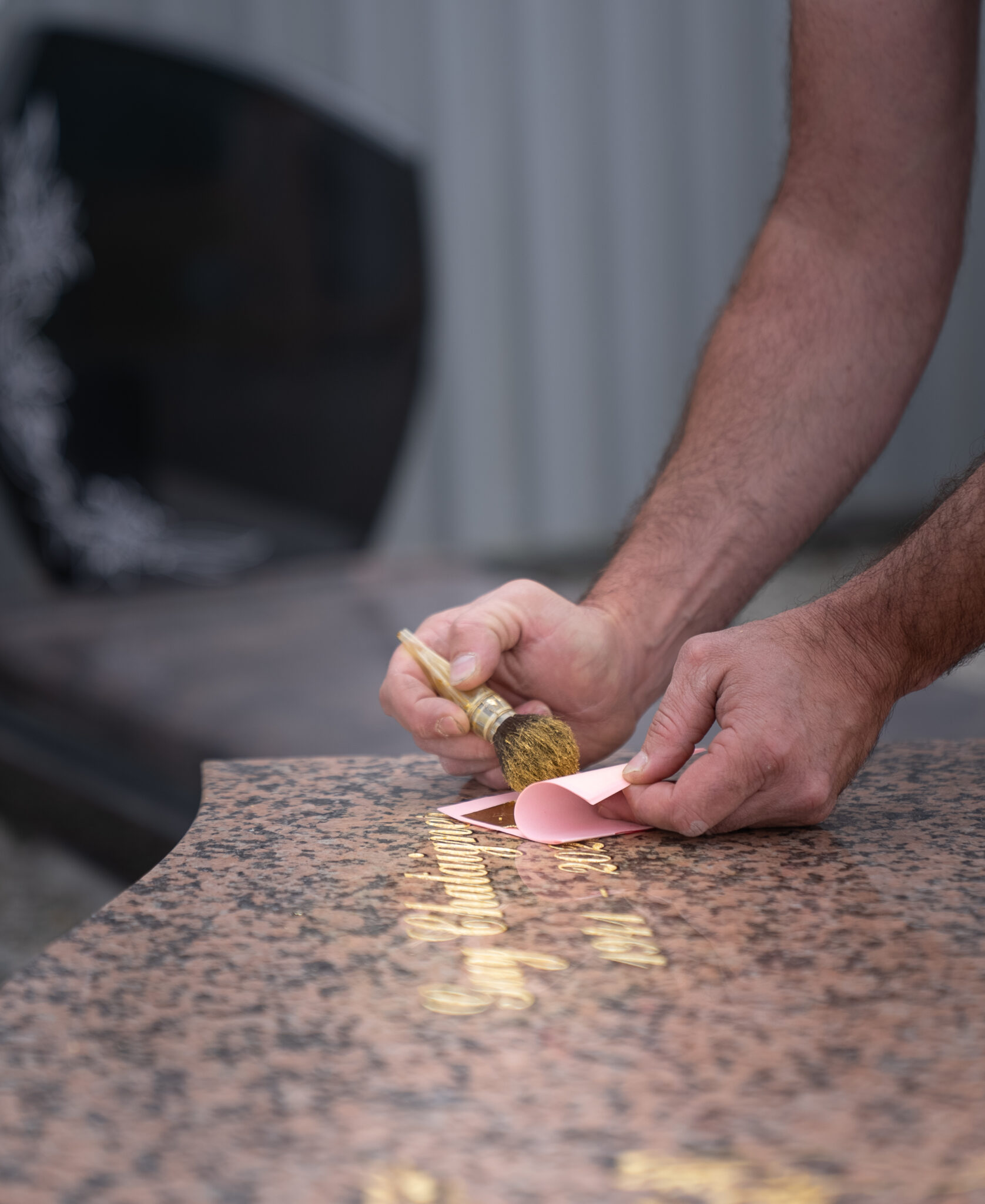 Personne nettoyant inscription sur pierre tombale.