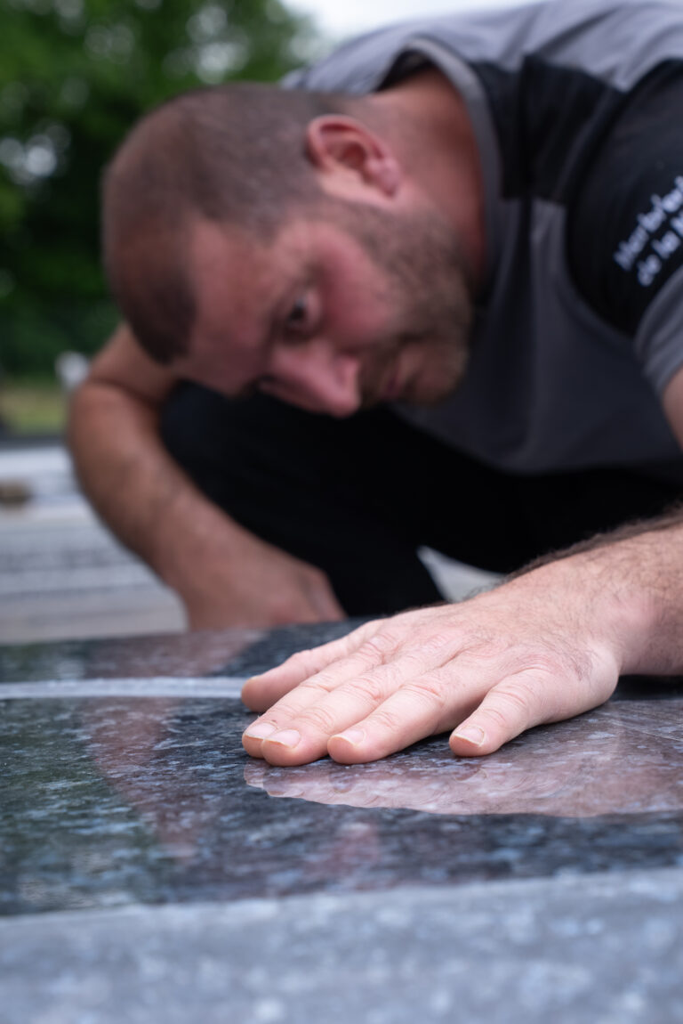 Homme touchant une surface de pierre polie.