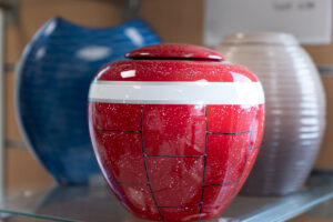 Urnes colorées exposées sur une étagère.