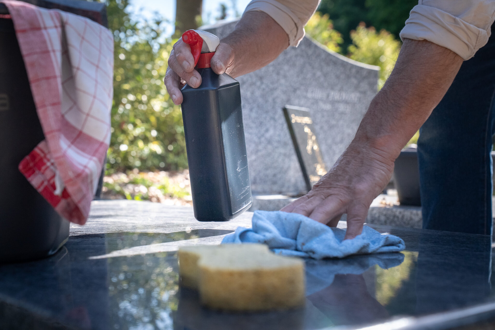 Nettoyage de pierre tombale avec chiffon et produit.