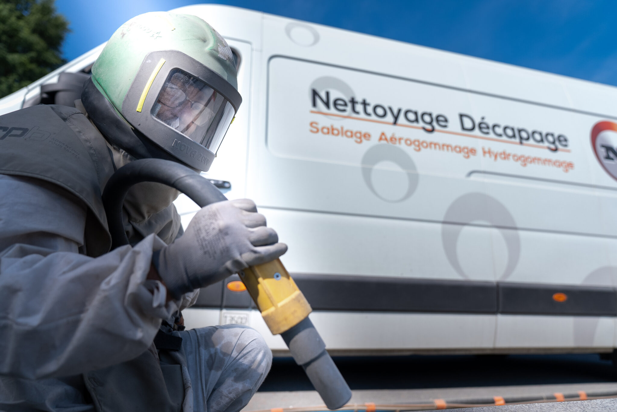 Travailleur sablage devant camion de nettoyage.